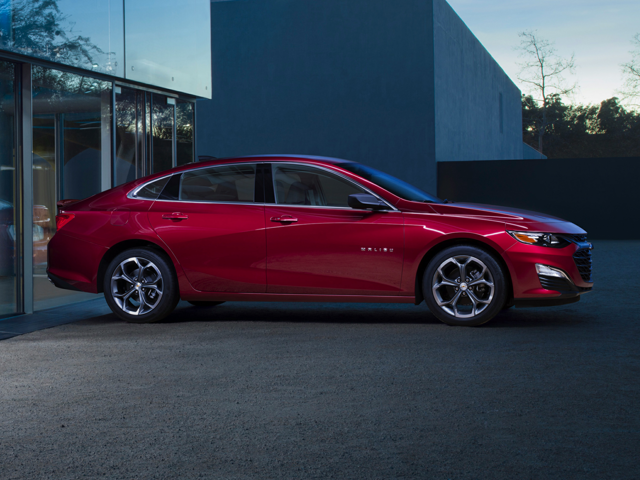 A red Chevy Malibu parked by a building