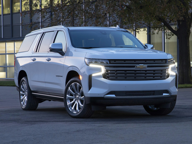A white Chevy Suburban parked outside near a building