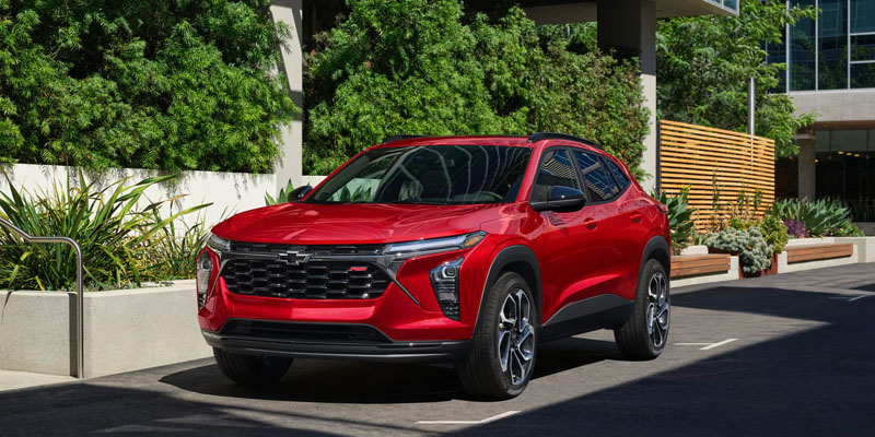 Red Chevrolet Trax parked outdoors in front of modern landscaping